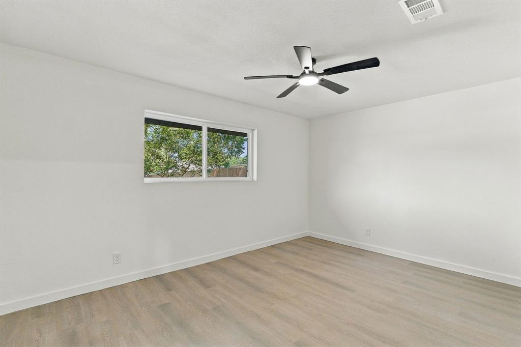 Neutral interior featuring wood-finish flooring, a contemporary ceiling fan with integrated lighting, and a single-pane horizontal window