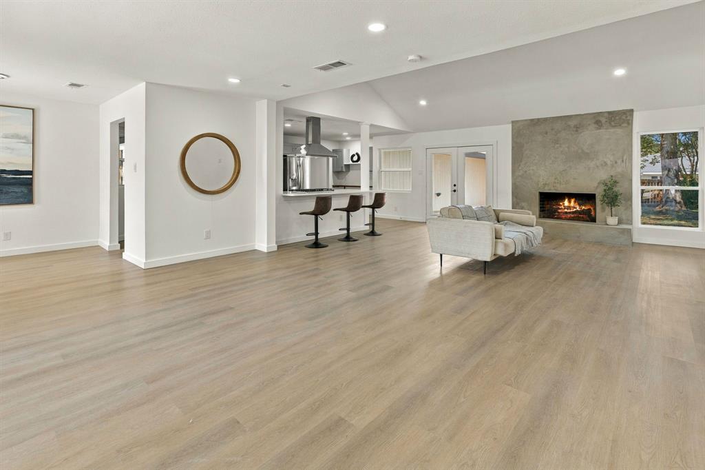 Open-concept floor plan featuring wood-finish flooring, vaulted ceilings, full-height masonry fireplace, and kitchen peninsula with bar-top seating