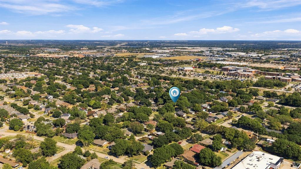 Aerial perspective featuring mature trees, established residential landscape, and proximity to regional commercial infrastructure