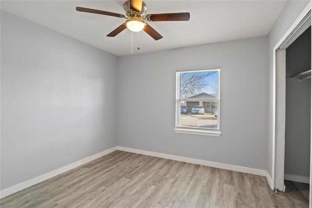Wood-finish flooring, neutral wall tones, multi-blade ceiling fan with integrated lighting