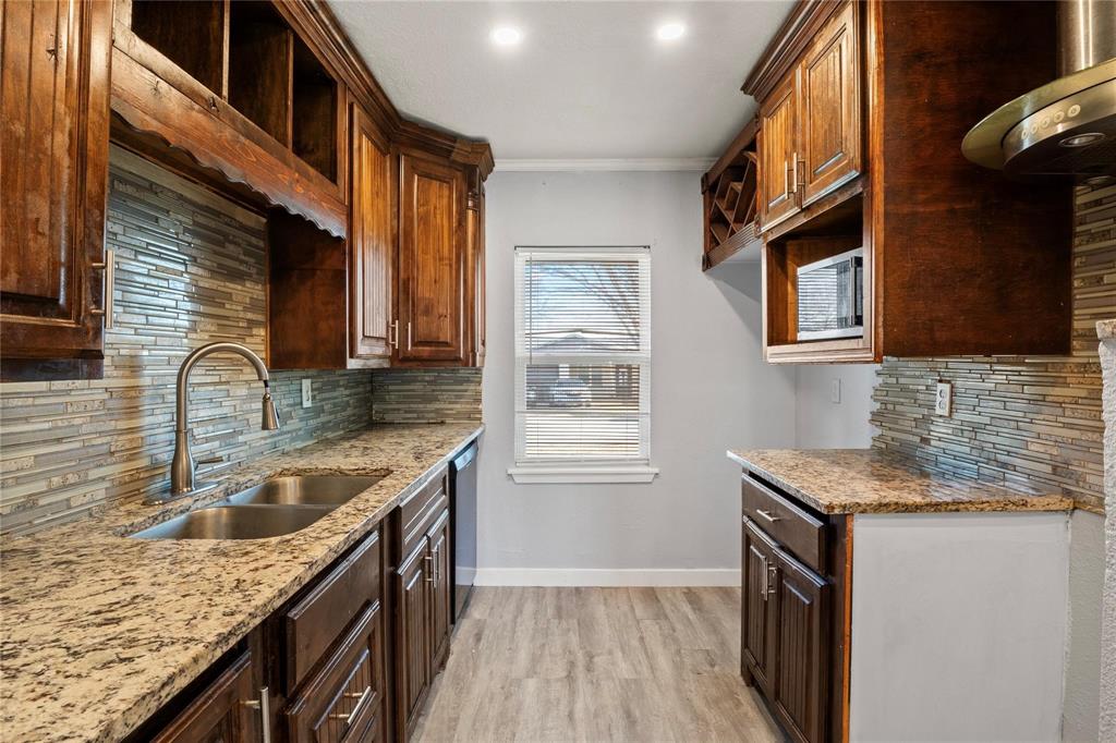 Kitchen featuring stained wood cabinetry, stone-patterned countertops, a stacked stone backsplash, wood-finish flooring, and a stainless steel gooseneck faucet