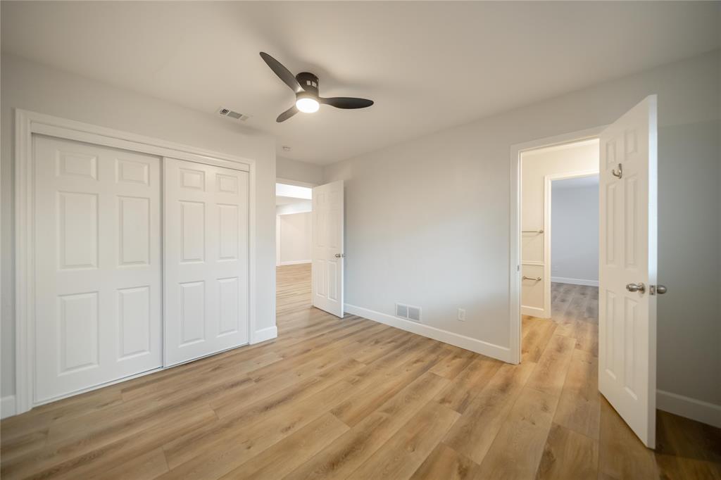 Room featuring wood-finish flooring, a matte black three-blade ceiling fan with integrated lighting, and white six-panel interior doors