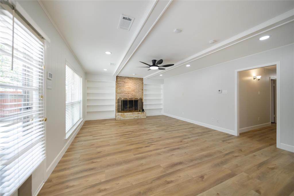 Living area featuring wood-finish flooring, a masonry fireplace with built-in shelving, recessed lighting, and a ceiling fan