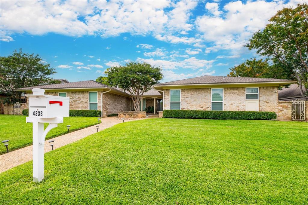 Single-story brick exterior featuring a hip roof, stone-paved walkway, mature landscaping, and decorative iron gates Single-story brick exterior featuring a hip roof, stone-paved walkway, mature landscaping, and decorative iron gates