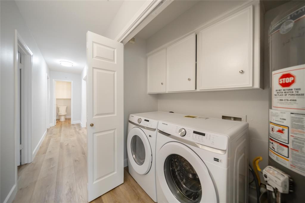 Laundry area featuring white shaker-style wall-mounted cabinetry, wood-finish flooring, and a six-panel interior door