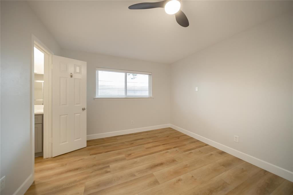 Room featuring wood-finish flooring, a neutral paint palette, a sliding window, and a three-blade ceiling fan with integrated lighting