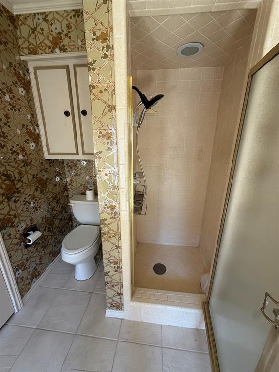 Bathroom featuring a tiled stand-alone shower with a glass enclosure, wall-mounted cabinetry, and ceramic tile flooring
