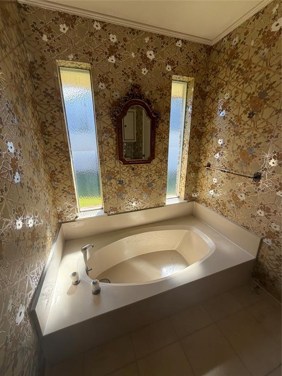 Built-in soaking tub with a surrounding deck, two vertical privacy-glass windows, and a wall-mounted towel bar
