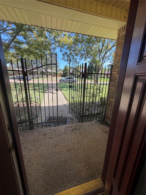 Covered porch featuring a concrete surface, decorative metal security gate, and exterior brick masonry Covered porch featuring a concrete surface, decorative metal security gate, and exterior brick masonry