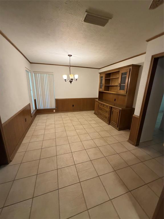 Tiled flooring, wood wainscoting, built-in wooden cabinetry, and a multi-light chandelier Tiled flooring, wood wainscoting, built-in wooden cabinetry, and a multi-light chandelier