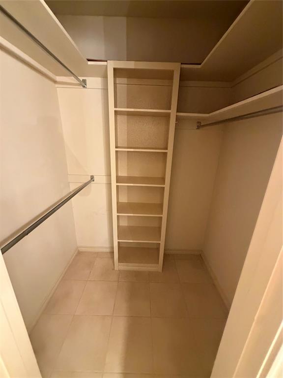 Storage area featuring tile flooring, built-in shelving, and metal hanging rods