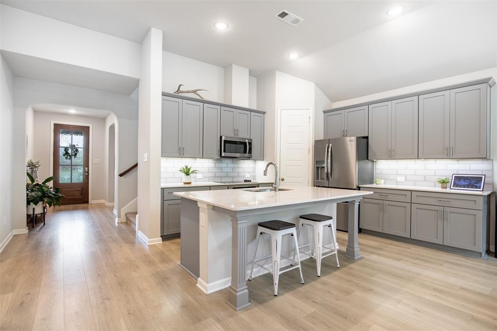 Beautiful kitchen features grey cabinetry, generous island with seating area, subway tile backsplash, and pantry.