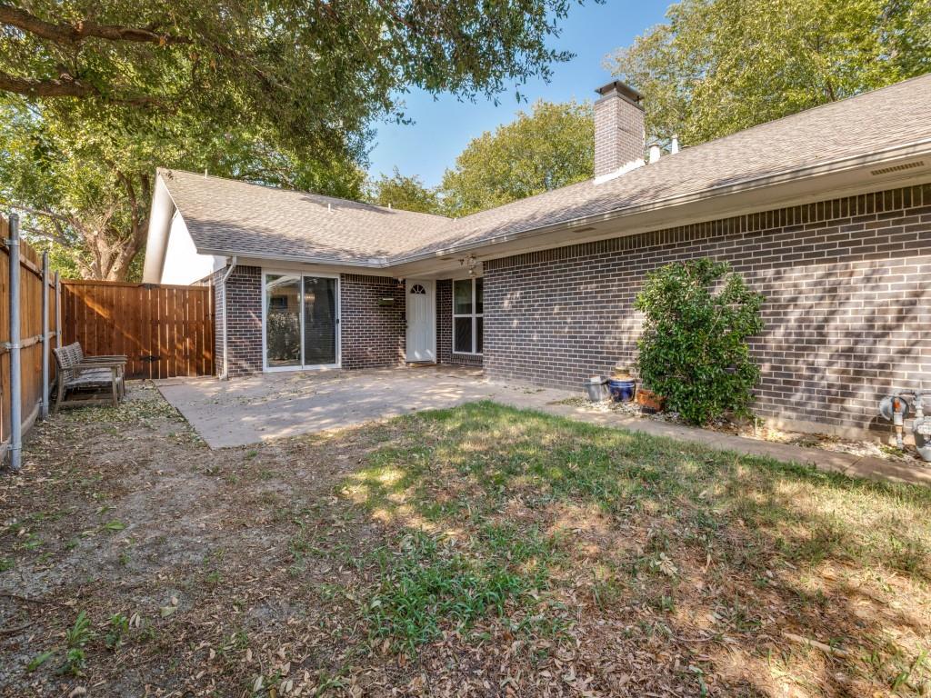 Brick exterior featuring a masonry chimney, concrete patio, and wood privacy fencing
