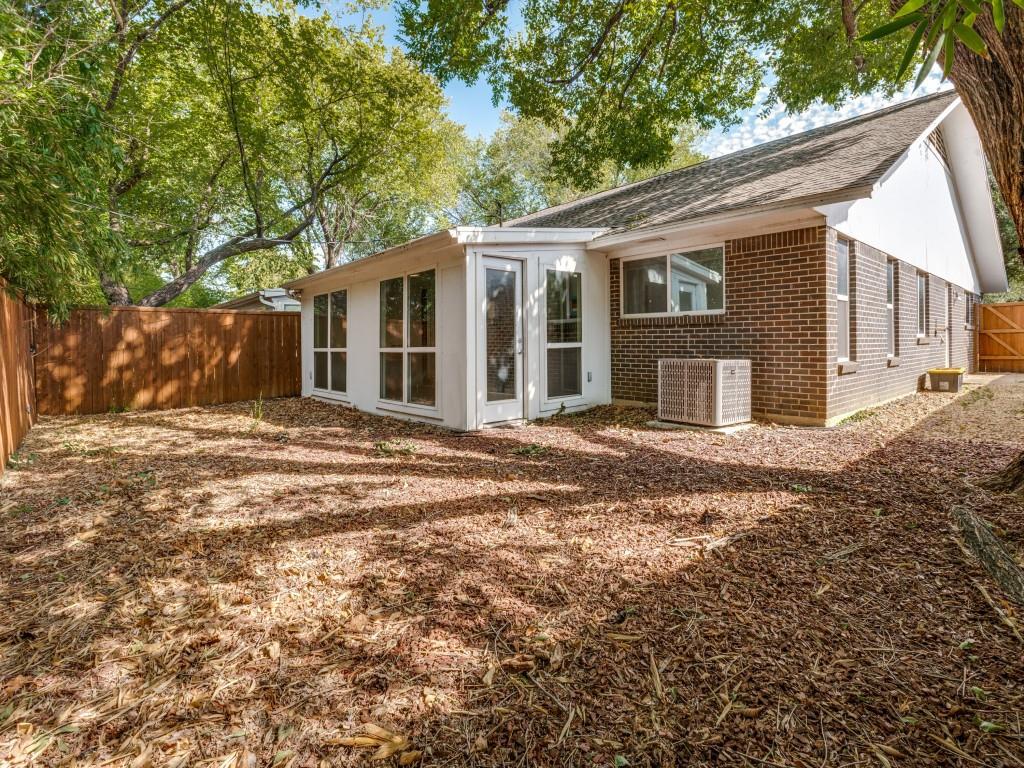 Brick exterior, enclosed sunroom with glass paneled doors, large-format windows, wood privacy fencing, and mature trees
