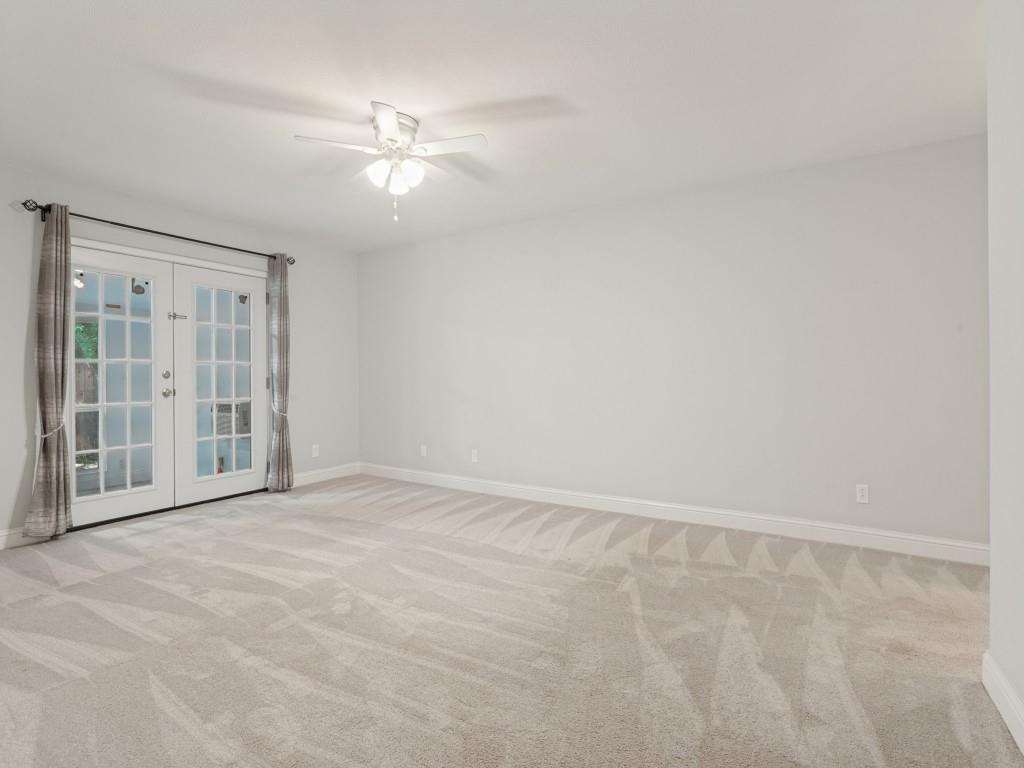 Neutral wall-to-wall carpeting, ceiling fan with integrated lighting, and full-glass panel French doors