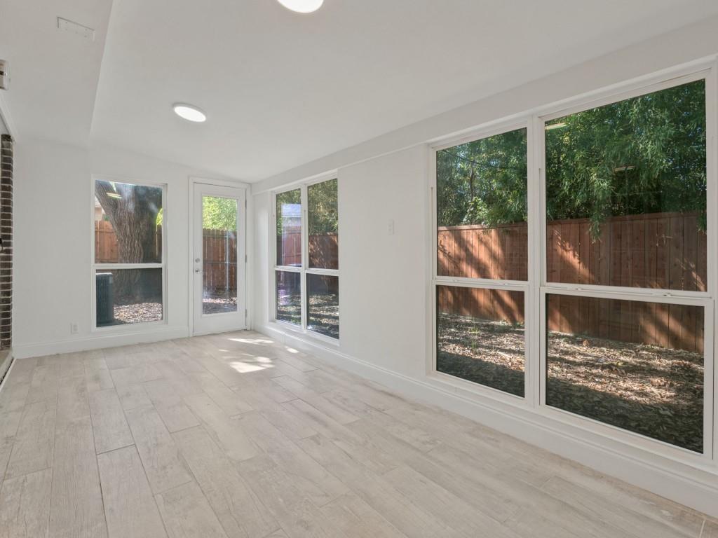 Light-filled room featuring neutral wood-finish flooring, recessed lighting, expansive picture windows, and a glass-paneled exterior door