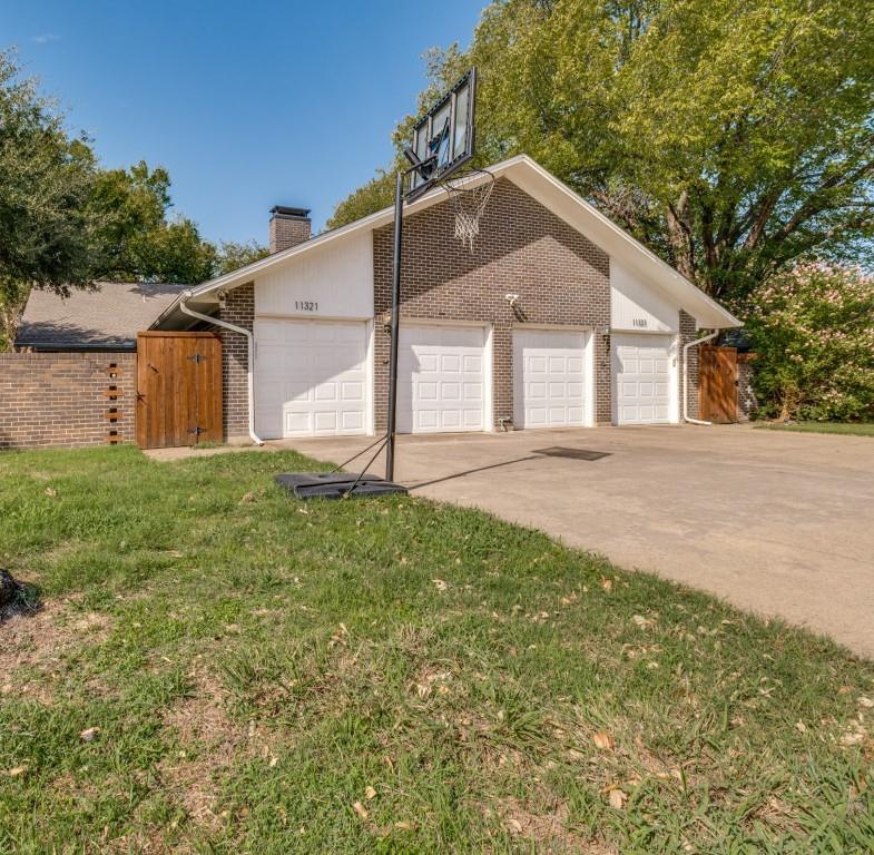 Four-car garage with white paneled doors, brick exterior cladding, and wood-paneled privacy fencing