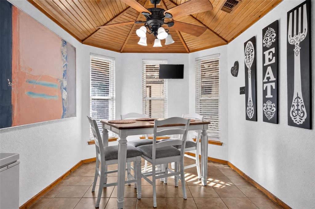 Octagonal ceiling featuring wood-plank paneling, multi-light ceiling fan, three paneled windows with blinds, and tile flooring