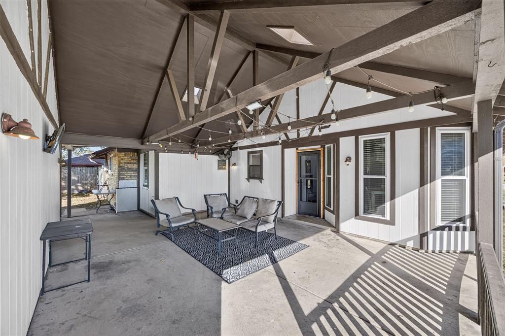 Covered patio featuring a vaulted ceiling with exposed beams, skylights, and concrete flooring