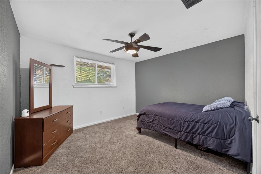 Neutral-toned carpet flooring, accent wall, ceiling fan with integrated lighting, and horizontal window