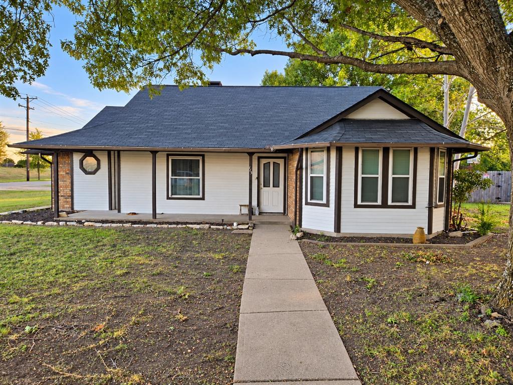 Single-story exterior featuring painted masonry siding, a covered front porch with support pillars, an extended roofline, a bay window, and a prominent octagon-shaped accent window