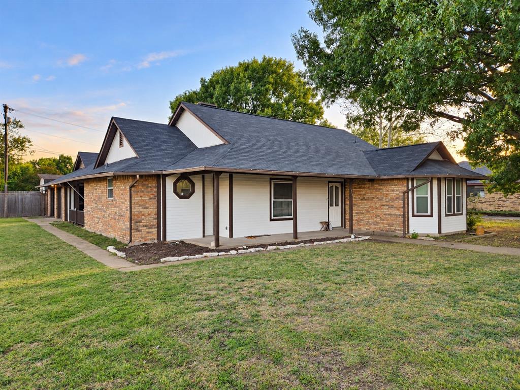 Exterior featuring a combination of brick and siding, a multi-gabled roofline, a covered wrap-around porch, a decorative octagonal window, and an expansive lawn