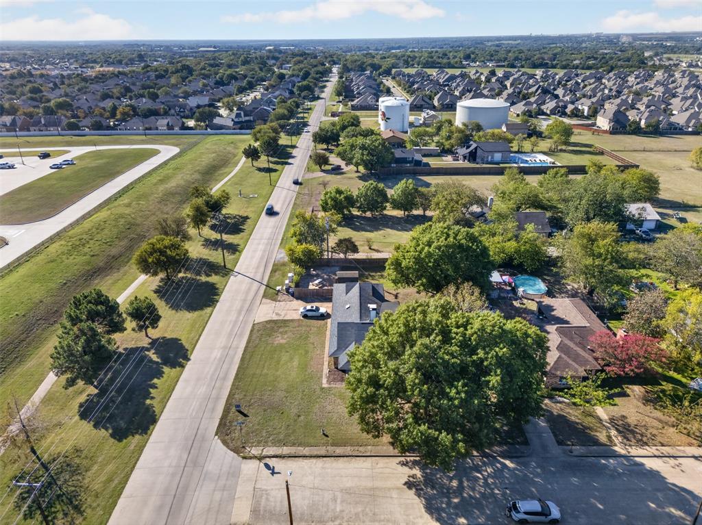 Aerial perspective featuring a residential lot with mature trees, a rectangular in-ground pool, and a multi-section shingled roof