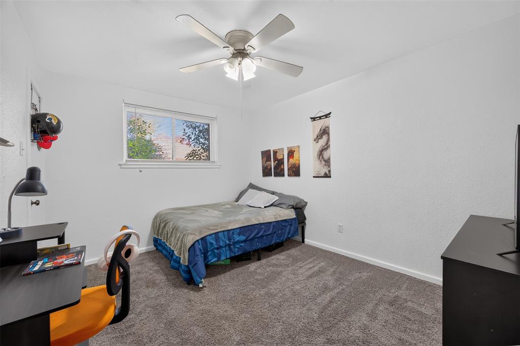 Room featuring neutral wall finishes, wall-to-wall carpeting, a multi-blade ceiling fan with integrated lighting, and a sliding window