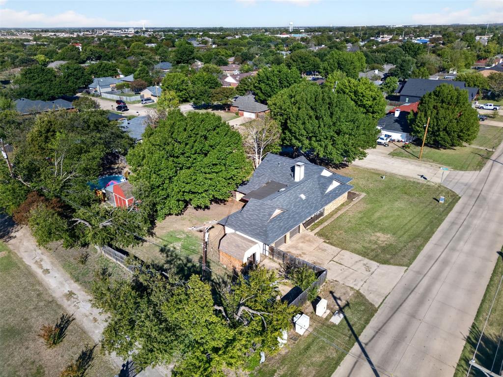 Aerial perspective of a multi-gabled roofline residence featuring an attached garage, paved driveway, detached storage structure, and expansive lot with mature tree canopy