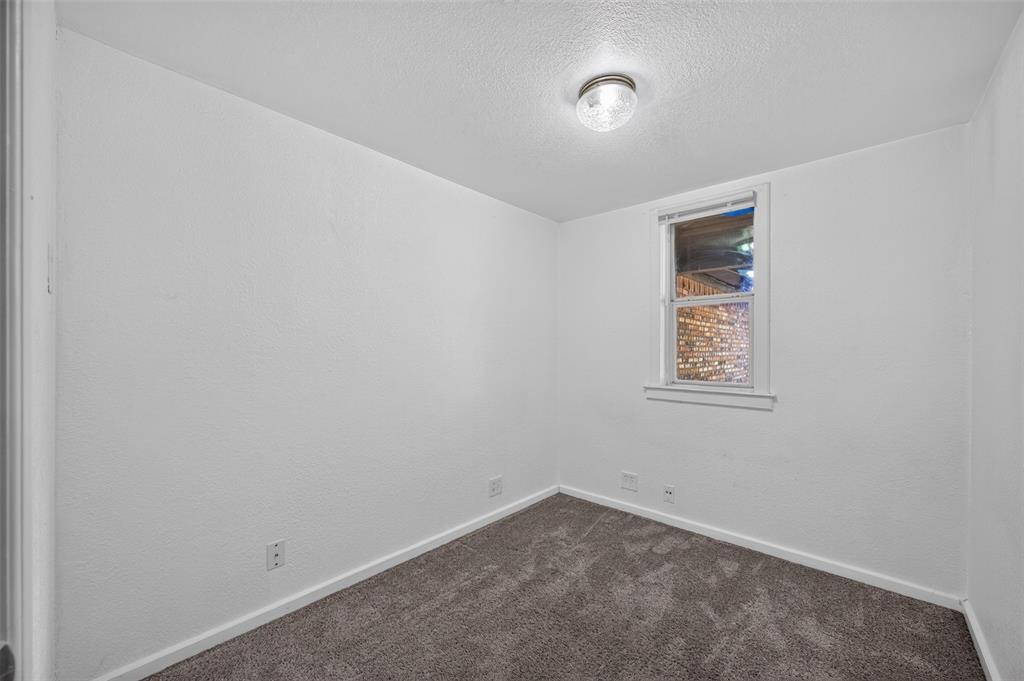 Neutral-toned carpeting and a single-hung window with a sill and white casing, accented by a centered flush-mount ceiling fixture