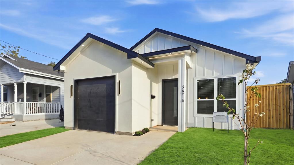 Modern exterior featuring board-and-batten siding, a single-car garage with black door, concrete driveway, recessed soffit lighting, and high-contrast dark window trim