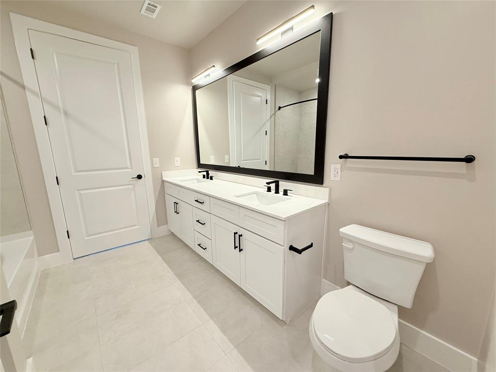 Bathroom with double vanity and light tile patterned flooring
