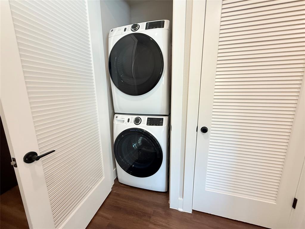 Laundry area featuring dark wood finished floors and stacked washer and clothes dryer