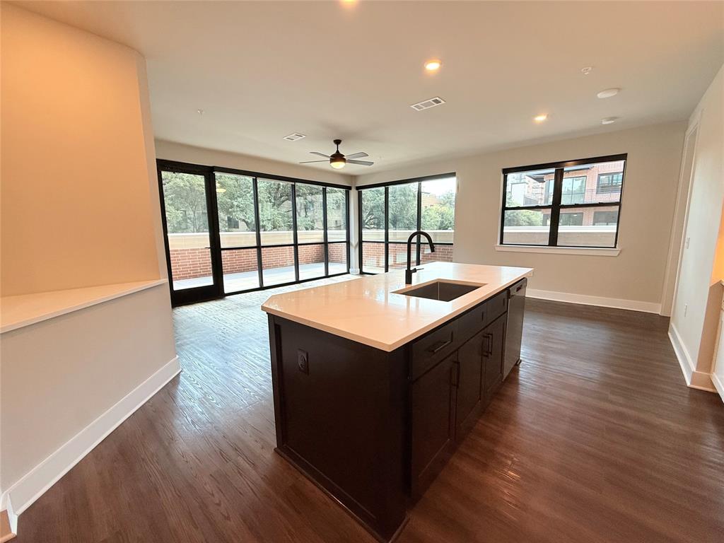 Kitchen with dark wood-type flooring, recessed lighting, an island with sink, a ceiling fan, and open floor plan