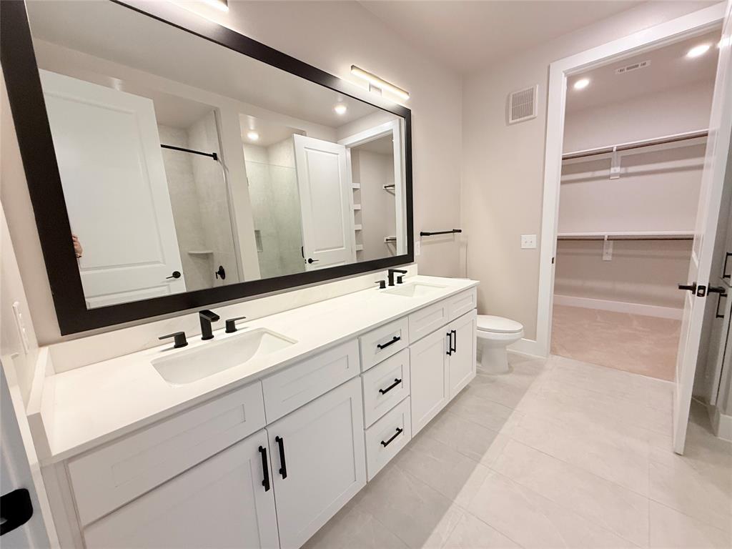 Full bath featuring a shower stall, double vanity, a walk in closet, recessed lighting, and light tile patterned flooring