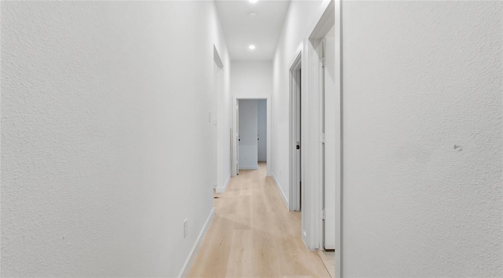 Hallway featuring light-toned wood-finish flooring, crisp white walls, and recessed ceiling lighting