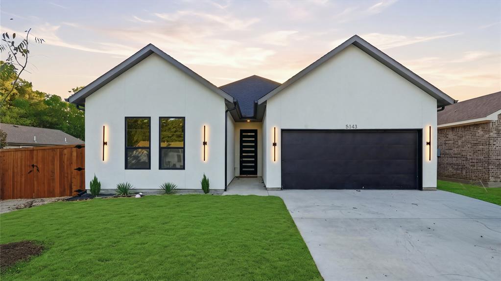 Modern exterior featuring a smooth stucco facade, dual-gabled roofline, horizontal-slat front door, and linear wall-mounted exterior lighting