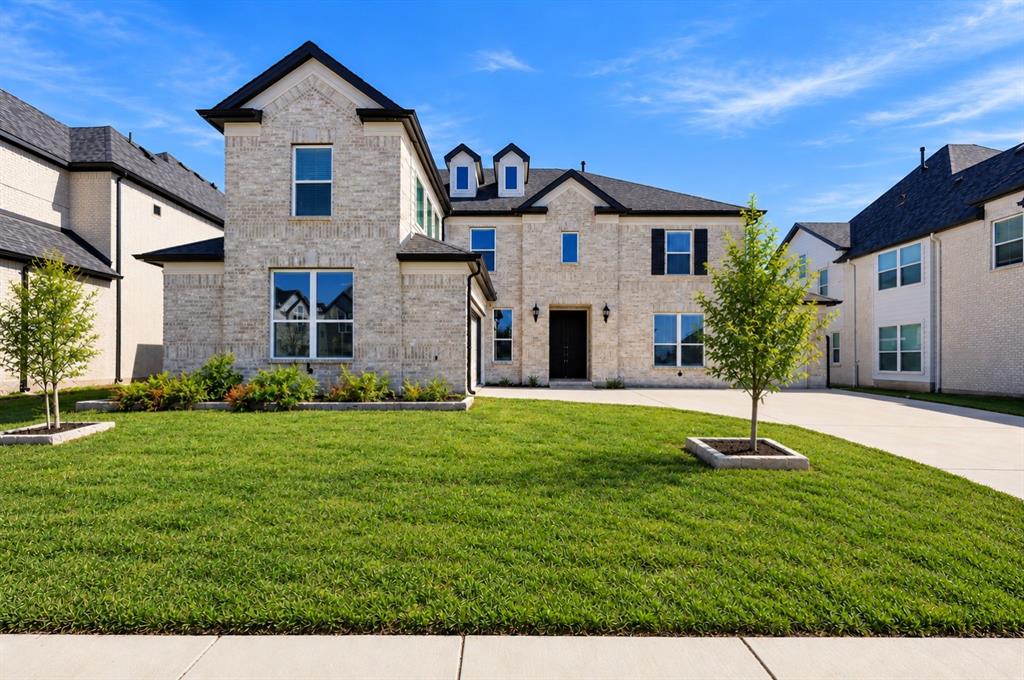 Two-story brick exterior featuring a multi-gabled roofline, dormer windows, shutters, and a concrete driveway Two-story brick exterior featuring a multi-gabled roofline, dormer windows, shutters, and a concrete driveway