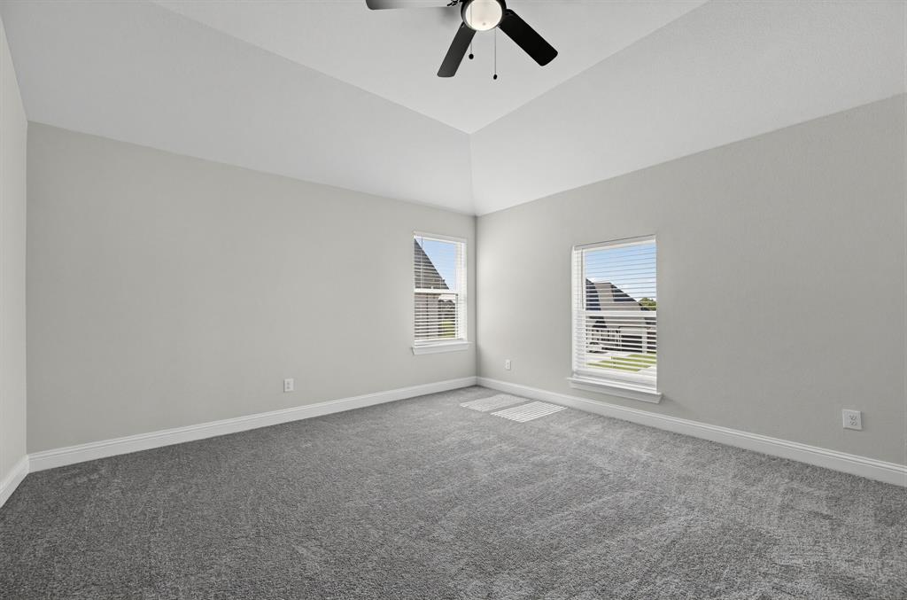 Vaulted ceilings, neutral wall color, carpeted flooring, and a ceiling fan with integrated lighting