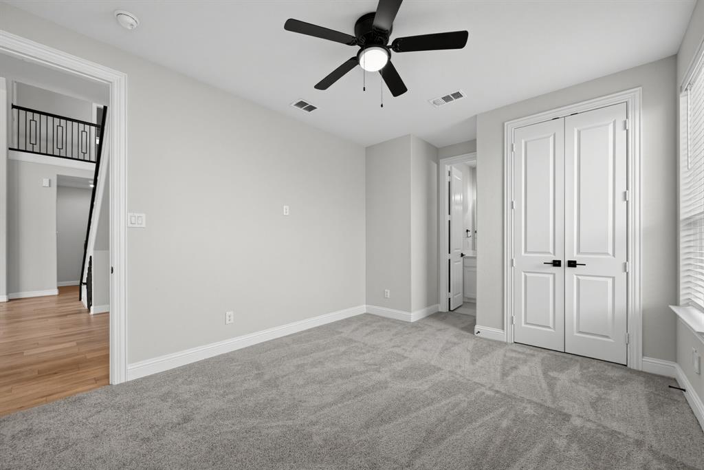 Neutral-toned room featuring plush carpeting, a ceiling fan with integrated lighting, and double doors with matte black hardware