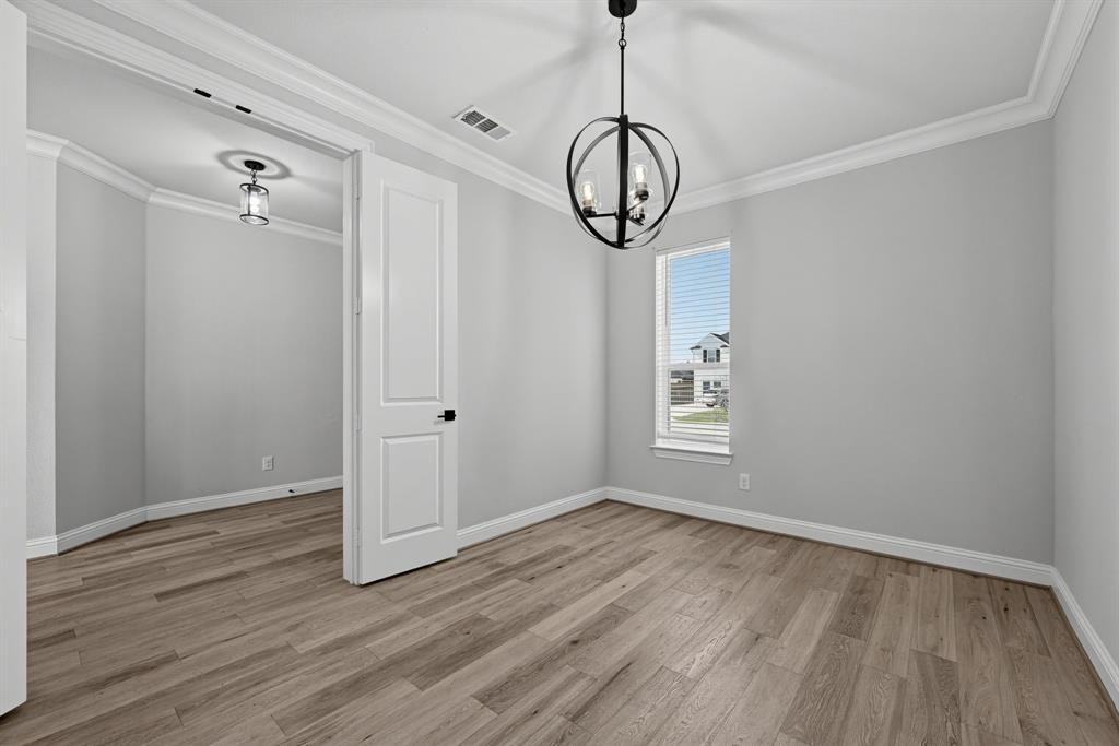 Interior room featuring wood-finish flooring, crown molding, a spherical metal chandelier, and a single-panel interior door