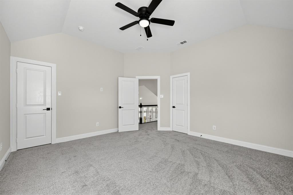 Vaulted ceilings, carpeted flooring, matte black hardware, three-panel interior doors, and a ceiling fan with integrated lighting