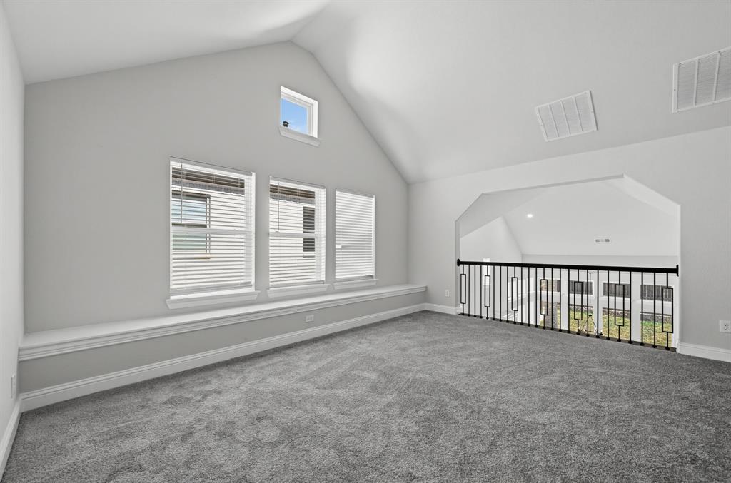 Vaulted ceilings, built-in window seating, triple-pane windows, and a black metal railing overlooking the lower level