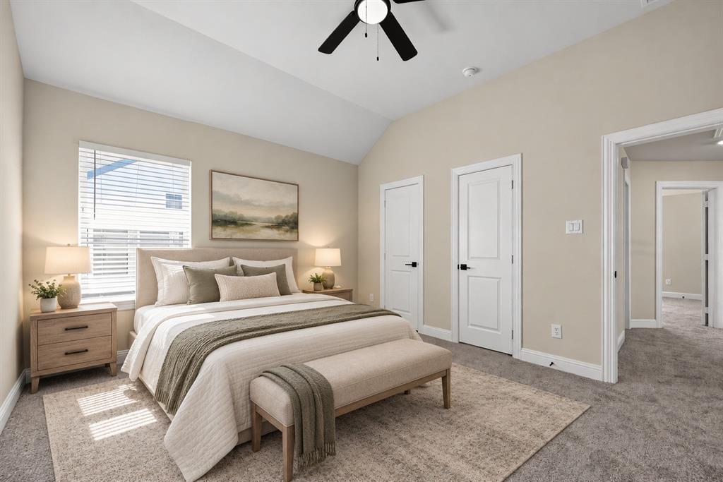 Vaulted ceiling featuring a central matte black ceiling fan, neutral wall tones, carpeted flooring, and white interior doors with matte black hardware