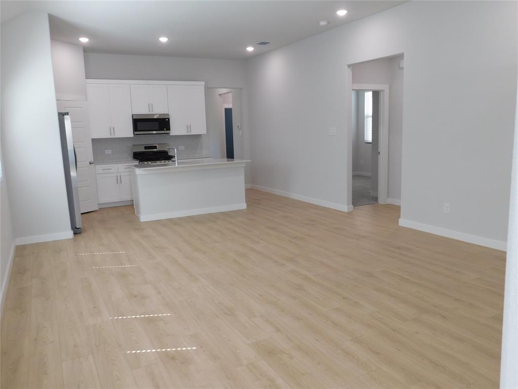Open-concept kitchen featuring white cabinetry, a peninsula, stainless steel appliances, and wood-finish flooring