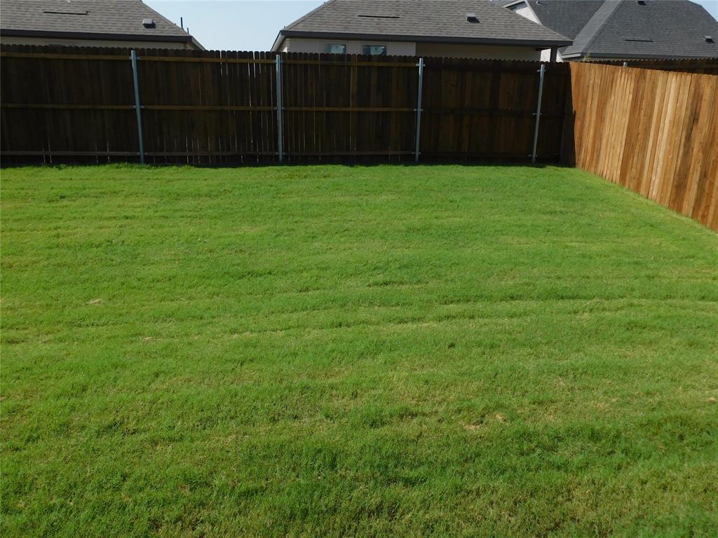 Backyard featuring a grass lawn enclosed by wood privacy fencing