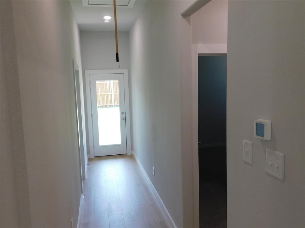 Hallway featuring light-toned wood-finish flooring, recessed lighting, and a glass-panel exterior door