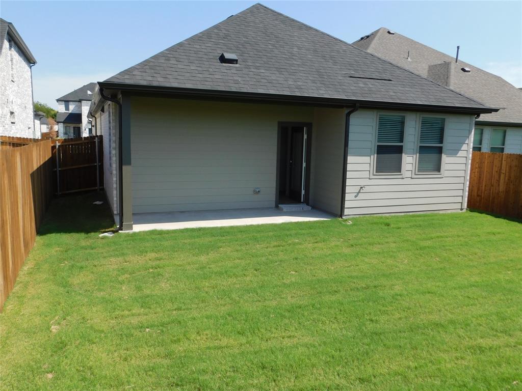 Rear exterior featuring a covered concrete patio, horizontal siding, composition shingle roof, and a fenced backyard with a grass lawn