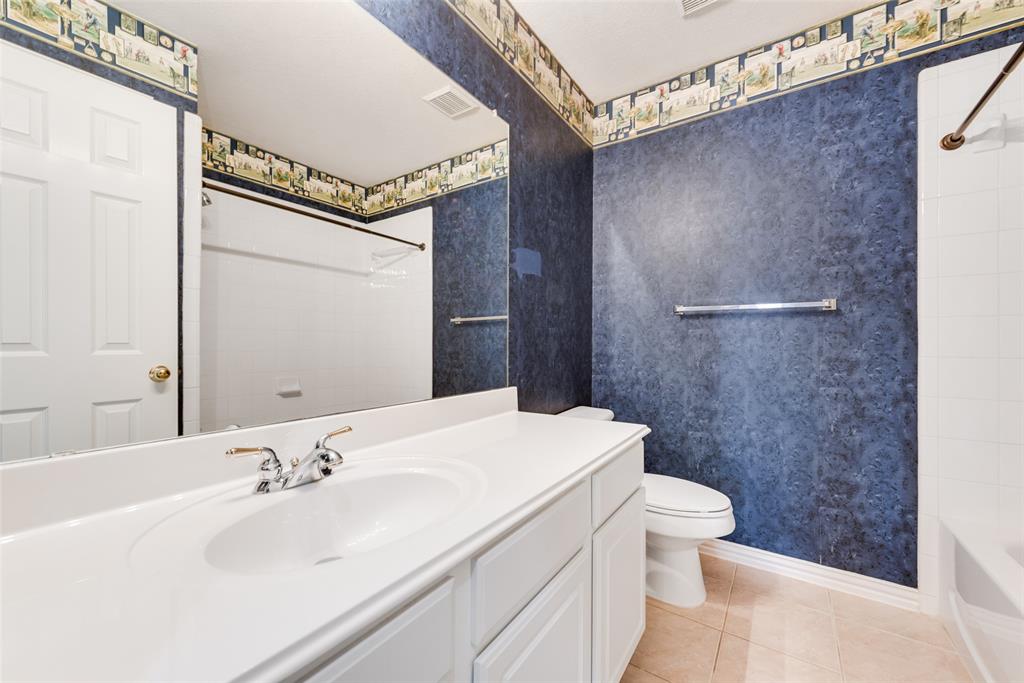 Bathroom featuring a white vanity with an integrated sink, large wall-mounted mirror, ceramic tile flooring, and a tub-shower combination with a surround