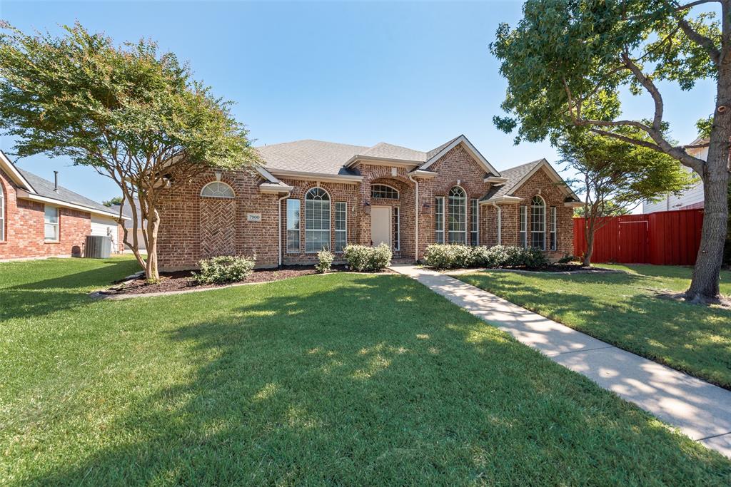 Single-story brick exterior featuring an arched entryway, gabled rooflines, arched window detailing, and a manicured front lawn with mature landscaping